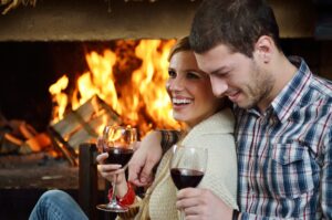 Couple drinking wine next to a fireplace